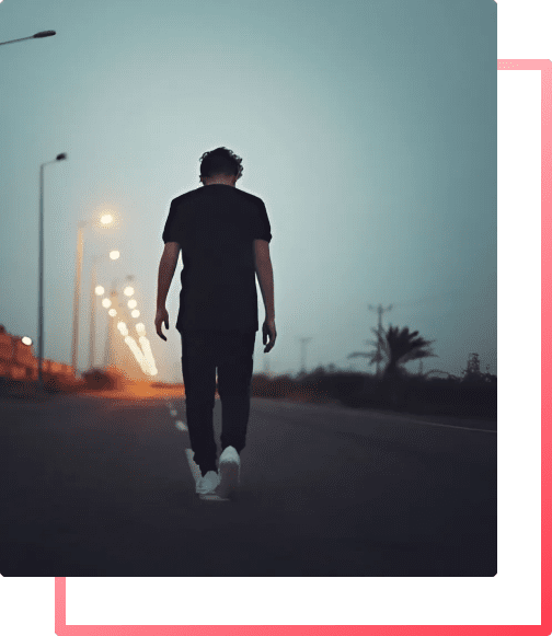 A man in anxiety and emotional distress walking down a road with his head down.